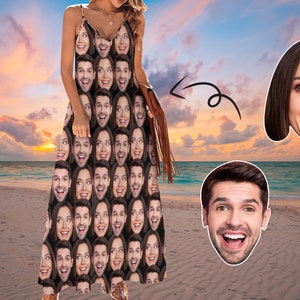 May include: A woman wearing a maxi dress with a pattern of many faces. The dress is brown and black. The woman is standing on a beach with a sunset in the background.