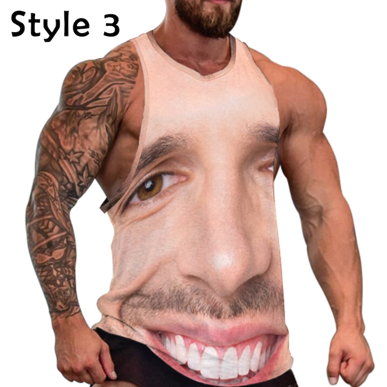 May include: A sleeveless tank top with a printed image of a man's face. The face is smiling and has a large nose and mouth. The tank top is a light brown color.