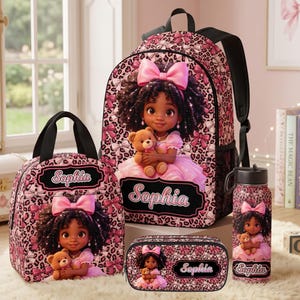 May include: A backpack, lunch bag, pencil case, and water bottle set featuring a pink leopard and bow print. Each item displays a cartoon illustration of a girl with dark curly hair, a pink dress, and a teddy bear, with the name Sophia printed.