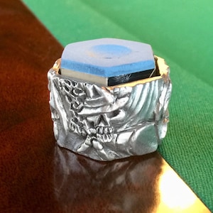 Peut inclure: Un porte-craie de billard en forme de crâne argenté avec un insert de craie bleu.