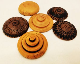 May include: Six wooden coasters with intricate black and brown designs. The coasters are round and have a smooth, polished finish.