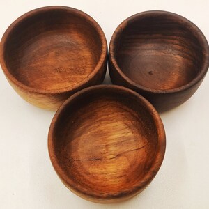 Peut inclure: Trois bols en bois, chacun avec un motif de grain unique. Les bols sont tous ronds et ont une finition lisse et polie.