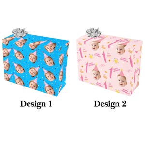 May include: Two wrapped gifts with silver bows. One gift is wrapped in blue paper with baby faces wearing party hats. The other gift is wrapped in pink paper with baby faces, cakes, and the text "Happy Birthday".