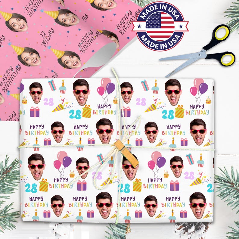 May include: Gift wrap featuring a repeating pattern of a person's face wearing sunglasses, balloons, gifts, and the words "Happy Birthday" and the number "28". A roll of wrapping paper with a face wearing a party hat is visible. Scissors and a "Made in USA" sticker are also present.