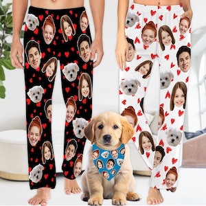 May include: A pair of black and white pajamas with a heart and face pattern. The pajamas are worn by a person. A golden retriever puppy is wearing a blue bandana with a face pattern. The puppy is sitting in front of the person wearing the pajamas.