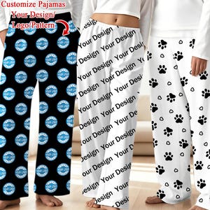 May include: Customisable pajama trousers in black, white, and white with paw prints. The black trousers feature a repeating logo pattern, while the white trousers display a repeating "Your Design" text. The third pair of trousers is white with black paw prints.