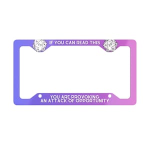 May include: A license plate frame in a gradient of purple to pink. The text "IF YOU CAN READ THIS" is at the top, and "YOU ARE PROVOKING AN ATTACK OF OPPORTUNITY" at the bottom. Two white dice are on either side of the frame.