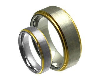 May include: Two silver wedding bands with a gold inlay. The bands are brushed and have a matte finish.