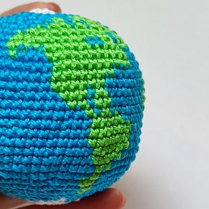May include: A crocheted globe with blue and green yarn, representing the Earth.