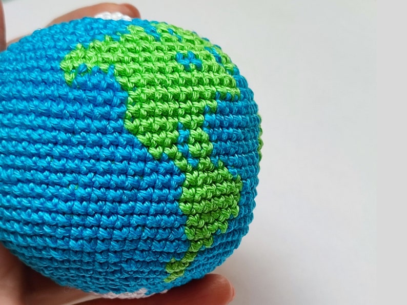 May include: A crocheted globe with blue and green yarn, representing the Earth.