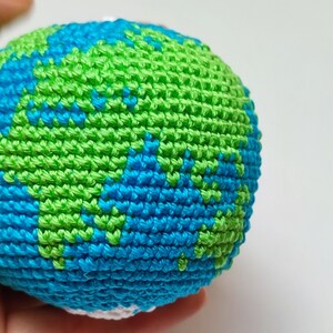 May include: A crocheted globe with blue and green yarn, representing the Earth.