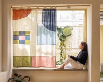 May include: A rectangular window curtain made of off-white fabric featuring a geometric pattern of various shapes and colors, including a red semi-circle, a blue square, a green and blue grid, and a pink rectangle, suspended from a wooden rod.