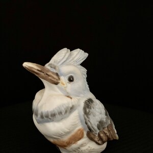 May include: A ceramic figurine of a blue and white bird with a long beak. The bird is sitting on a black surface.