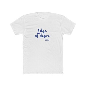 May include: A white short-sleeved t-shirt featuring the text Edge of desire in a blue cursive script font, with the name JOHN MAYER printed in smaller blue capital letters directly underneath the main text on the front of the garment.
