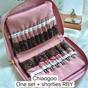 K&ouml;nnte beinhalten: Ein rosafarbenes Etui mit Rei&szlig;verschluss enth&auml;lt eine Sammlung von Stricknadelspitzen aus Metall und rote Kabel. Das Innere verf&uuml;gt &uuml;ber Stofff&auml;cher mit aufgedruckten Etiketten von 2,0mm bis 5,0mm. Text auf dem Bild: Chiaogoo One set + shorties RBY.