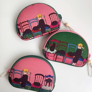 May include: Three small, semi-circular coin purses. Each purse features a pink fabric with a print of a person sitting in a chair, surrounded by other chairs. The purses have green trim and a zipper closure.