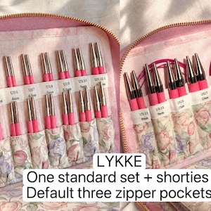 K&ouml;nnte beinhalten: Ein rosa Etui mit Rei&szlig;verschluss enth&auml;lt eine Sammlung von Lykke-Stricknadeln mit Metallspitzen und rosa Basen. Das Innere verf&uuml;gt &uuml;ber Taschen aus Blumenstoff, die mit metrischen Gr&ouml;&szlig;en von 3,25mm bis 12mm beschriftet sind.