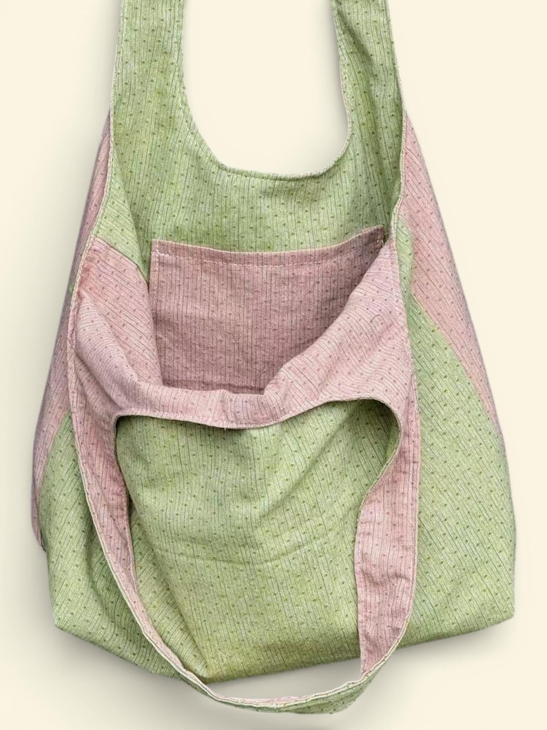 Pu&ograve; includere: Una grande borsa tote aperta con una tracolla. La borsa &egrave; realizzata in tessuto a righe verdi e rosa. La borsa ha una grande tasca sul davanti. La borsa &egrave; realizzata in un tessuto morbido e strutturato.