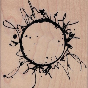 May include: Black ink splatter design with a circle in the center. The circle is outlined in black ink and has a rough, textured look. The splatter design is around the circle and is made up of small, thin lines and dots.