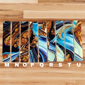 May include: A set of ten colorful, abstract, rectangular tiles with a blue, gold, and white marbled pattern. The tiles are labeled with the letters M through U.