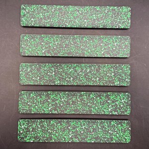 May include: Five rectangular, speckled green and black objects are arranged in parallel. The objects have rounded corners and a consistent pattern of green speckles on a black background. The items are evenly spaced.