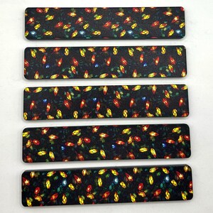 May include: Five rectangular decorative items with a black background and a repeating pattern of colorful, stylized lights in red, yellow, and blue. The lights are arranged in a random, organic pattern across the surface of each item.