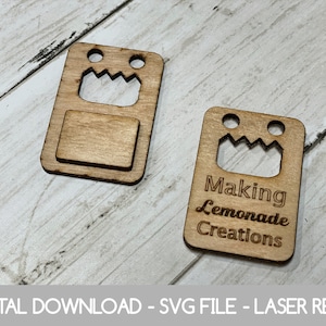 May include: Two laser cut wooden tags with a robot face design. One tag has a blank space for text and the other tag says "Making Lemonade Creations".