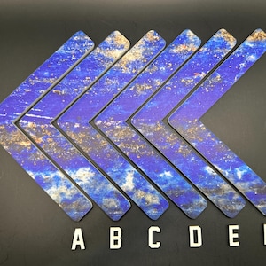 May include: Seven blue and gold chevron-shaped decorative pieces arranged in an arrow formation. The pieces have a marbled appearance with a mix of blue and gold tones. White letters A through F are at the bottom.