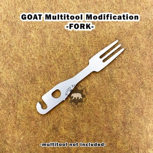 Op de afbeelding: Een zilverkleurige GOAT Multitool Modification - FORK. De vork heeft drie tanden en een haak aan het handvat. De tekst "GOAT Multitool Modification -FORK-" staat bovenaan de afbeelding. De tekst "-multitool not included-" staat onderaan.
