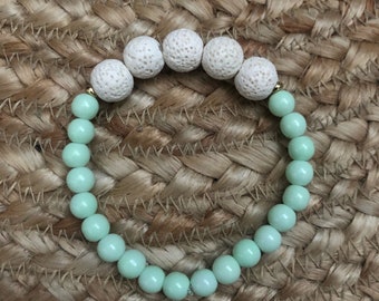 May include: A bracelet made of light green and white beads. The white beads are lava rock and the green beads are smooth and round.