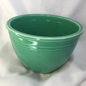 May include: A large, green ceramic mixing bowl with a smooth, glossy finish. The bowl has a rounded bottom and a wide, flat rim.