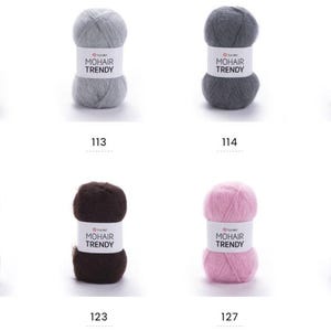 May include: Eight balls of mohair yarn in a range of colours: green, grey, dark grey, brown, pink, and blue. Each ball has a label reading "MOHAIR TRENDY" and a number. Suitable for knitting and crochet projects.
