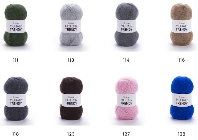 May include: Eight balls of mohair yarn in a range of colours: green, grey, dark grey, brown, pink, and blue. Each ball has a label reading "MOHAIR TRENDY" and a number. Suitable for knitting and crochet projects.