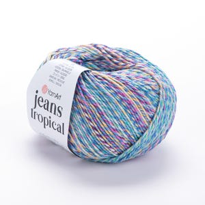Op de afbeelding: Een bol YarnArt Jeans Tropical garen in tinten blauw, paars, geel en wit. Het garen is verpakt met een wit label met de tekst "YarnArt jeans tropical". Het garen is een mix van katoen en acryl.