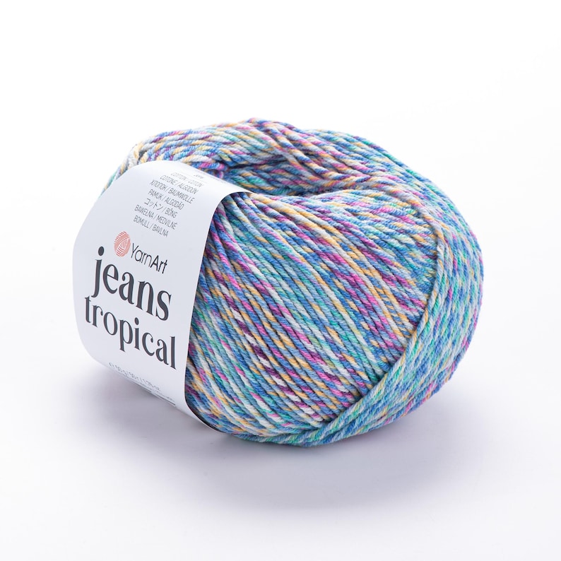 Op de afbeelding: Een bol YarnArt Jeans Tropical garen in tinten blauw, paars, geel en wit. Het garen is verpakt met een wit label met de tekst "YarnArt jeans tropical". Het garen is een mix van katoen en acryl.