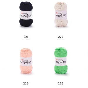 May include: A selection of YarnArt Creative yarn balls in various colours, including white, black, cream, tan, yellow, light pink, green, and dark green. Each ball has a label with "creative" printed on it and a number from 220 to 227 below.