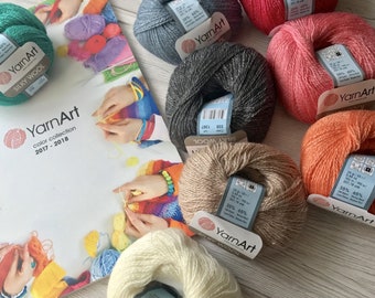 May include: A selection of YarnArt Silky Wool yarn balls in shades of teal, grey, pink, and beige. The image also shows a catalogue with the YarnArt logo and the text "color collection 2017-2018". Each ball weighs approximately 25g.