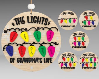 May include: A round wooden ornament with the text "The Lights of Grandma's Life" and a string of colorful light bulbs with names written on them.