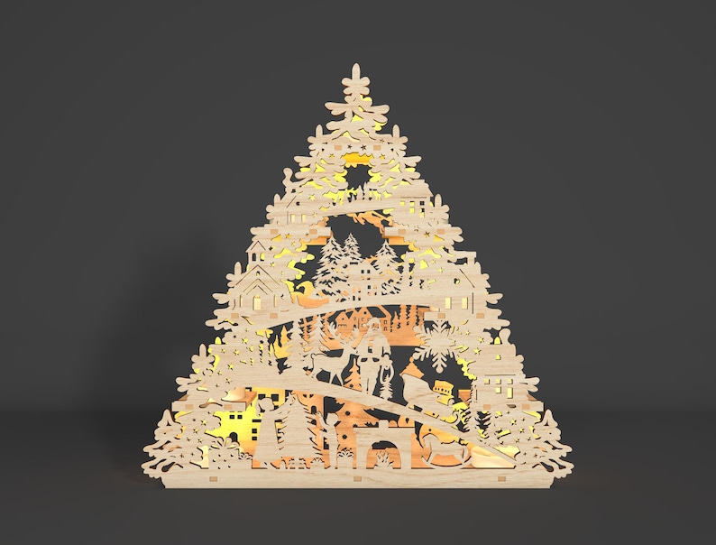 May include: A wooden Christmas tree decoration featuring a detailed design of a winter village scene. The ornament is illuminated with warm white lights, creating a festive glow.