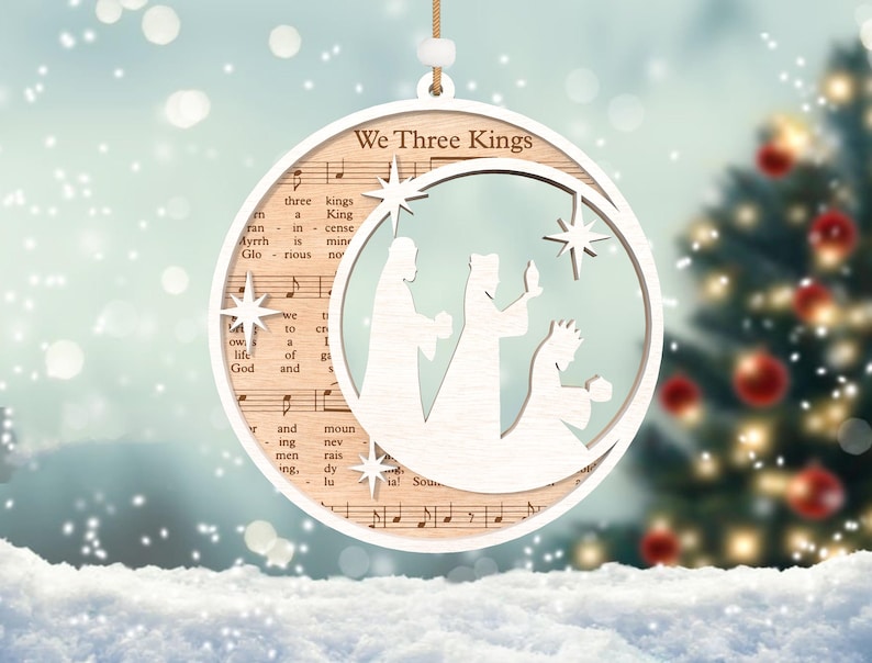 Puede incluir: Adorno navide&ntilde;o de madera blanco con un recorte de los tres reyes magos y una estrella. El adorno est&aacute; decorado con notas musicales y las palabras "We Three Kings".