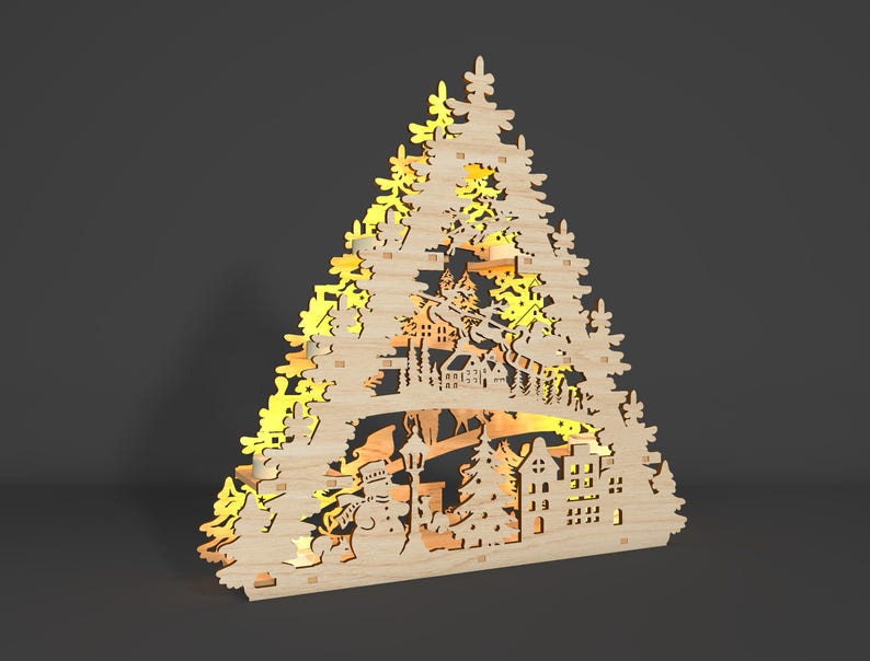 May include: A wooden Christmas tree decoration featuring a cut-out design of a winter village scene. The decoration is lit with warm white lights, creating a festive glow.