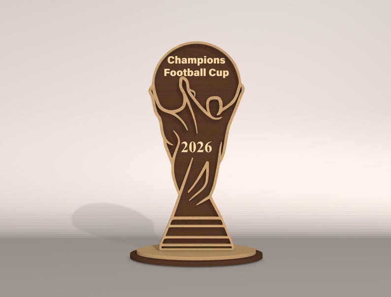 May include: A wooden Champions Football Cup trophy with the year 2026. The trophy is brown with a light brown outline and sits on a round base. The text "Champions Football Cup" is at the top.
