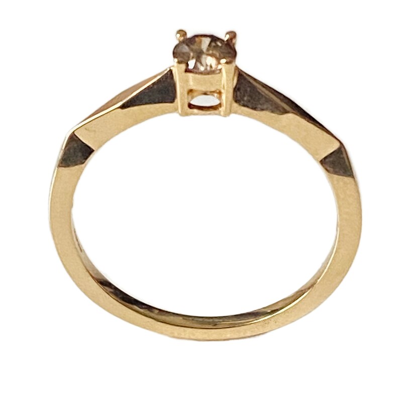 Puede incluir: Un anillo de oro con una sola piedra preciosa redonda peque&ntilde;a y transparente engastada en el centro.