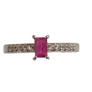 May include: A silver ring featuring a pink rectangular gemstone set in a band of small diamonds.