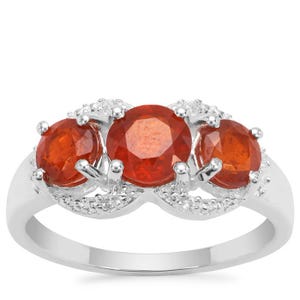 K&ouml;nnte beinhalten: Ein silberner Ring mit drei runden orangefarbenen Edelsteinen, die in einem dekorativen Design gefasst sind. Der Ring ist mit kleinen wei&szlig;en Edelsteinen verziert.