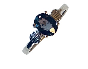 May include: A silver ring with a dark blue oval gemstone set in a delicate, ornate design.