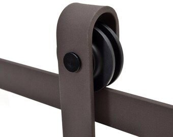 May include: Close-up of a brown metal barn door hardware kit with a black roller and a black knob. The hardware is designed for sliding doors.