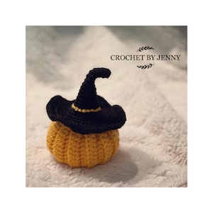 May include: A crocheted pumpkin with a black witch hat. The pumpkin is yellow and the hat has a gold trim.