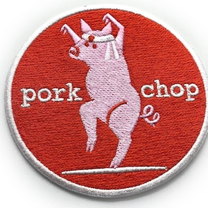 Puede incluir: Un parche rojo bordado con un contorno blanco que presenta un cerdo rosa haciendo una pose de karate. El texto "pork chop" está bordado en blanco en el parche.