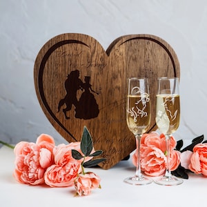 May include: A wooden heart-shaped box with a laser-engraved design of Belle and the Beast from Beauty and the Beast. The box is decorated with the names "David & Jenny" and the date "September". Two champagne flutes are engraved with the same design and the names "Jenny" and "David".